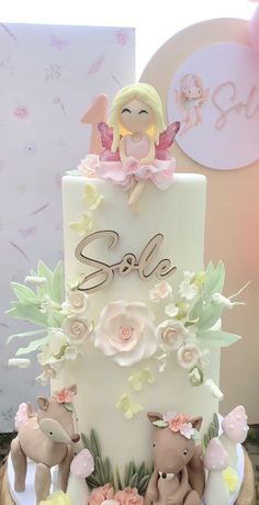 a white cake with pink flowers and an angel figurine sitting on top of it