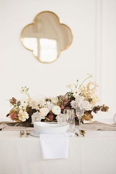 the table is set with white flowers and silverware