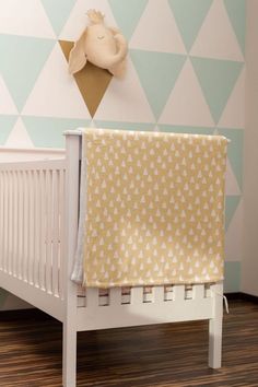 a baby crib with a blanket on top of it in front of a wall