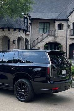 a black suv parked in front of a large house