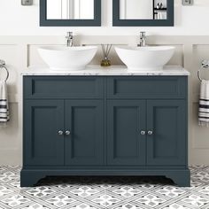 two sinks and mirrors in a bathroom with grey cabinets, white counter tops and patterned floor tiles