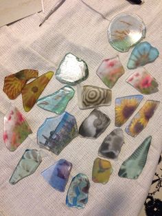 a table topped with lots of different colored pieces of glass on top of a white cloth