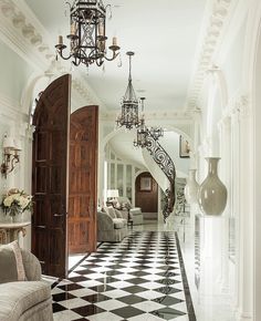 an elegant foyer with black and white checkered flooring, chandelier and two couches