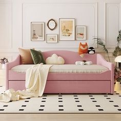 a living room with a pink couch and pictures on the wall