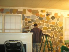 a man painting a stone wall in his living room