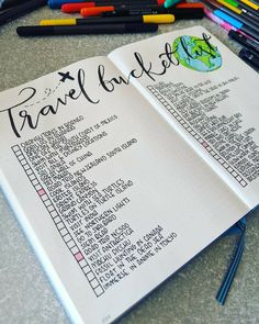 an open travel book sitting on top of a table filled with markers and pencils