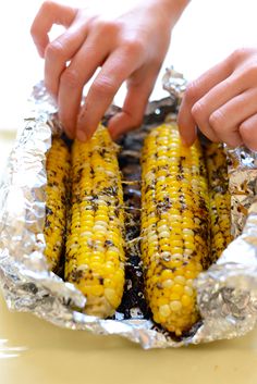 someone is peeling corn on the cob in foil