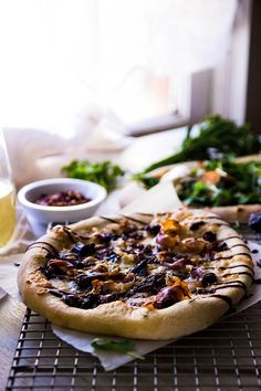 a pizza sitting on top of a cooling rack next to a bowl of salad and glass of wine