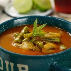 a blue bowl filled with soup and vegetables