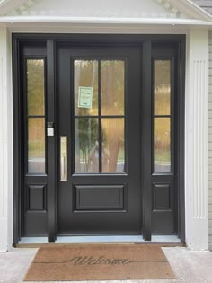 a black front door with two sidelights and glass panels on the top half of it