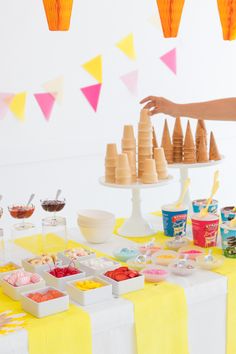 a table topped with ice cream cones and bowls filled with toppings on top of it