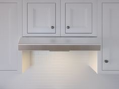 a kitchen with white cabinets and a stainless steel range hood