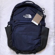 the north face backpack is laying on top of a white furnishing area with a tag attached to it