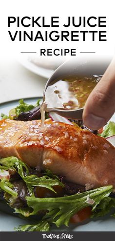 a person cutting into a piece of meat on top of a green leafy salad