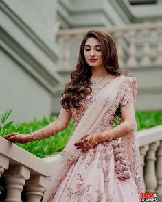 a woman in a pink lehenga standing on a balcony