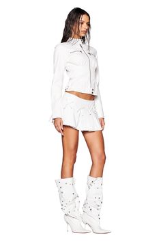 A person is wearing a white ensemble that includes a jacket and the EVERETTE SKORT - WHITE by I.AM.GIA, featuring a low-rise waist. They are donning knee-high boots embellished with studs. The individual has long, wet-looking hair and is positioned against a plain white background. Festival Jacket, I Am Gia, White Bow, Lingerie Romper, Buy Now Pay Later, Skirts For Sale, Invisible Zipper, Leather Mini, Right Side