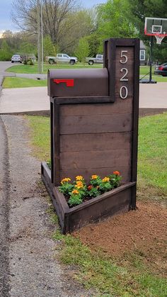 a mailbox with flowers growing in it on the side of a road next to a basketball hoop