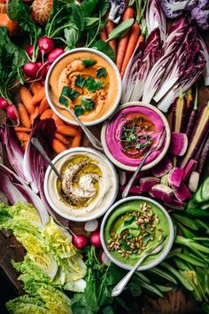 many different types of vegetables and dips on a table