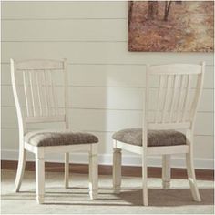 two white chairs sitting next to each other on a carpeted floor in front of a painting