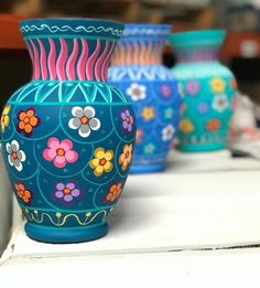 three colorful vases sitting on top of a white table next to eachother