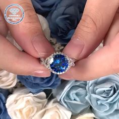 a woman's hand with a blue ring on top of it and roses in the background