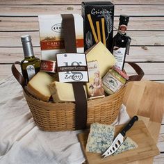 a basket filled with cheese and wine on top of a wooden table