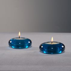 two blue candles sitting next to each other on a table