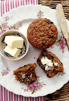 three muffins on a floral plate with butter and some blueberries next to it