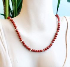 Red Jasper/garnet necklace with 6mm beads and zircons. MEASURES 35, 40, 45, 50, 55 and 60 cm. + 5cm extender.  There is the possibility of removing the extender in case you don't want it. Contact me to detail your request  💎M A T E R I A L S - 6mm Red Jasper semi-precious stones.   The stones are natural so they will never be the same as others. - Nickel-free and hypoallergenic brass fasteners. - Unbreakable steel thread for bead binding. 📦PACKAGING Very nice and original packaging, ready to give as a gift if desired. - Black aluminum can (measured according to the size of the jewel). - Organza bag, store card, discount VIP card, jewelry cleaning cloth    and some delicious sweets. - Padded bag for protection during transport. 📦 SHIPPING All products are sent with CERTIFIED Parcel of Co Red Jasper Necklace, Brass Fasteners, Red Jasper Stone, Vip Card, Pad Bag, Jasper Necklace, Garnet Necklace, Necklace Red, Jasper Stone