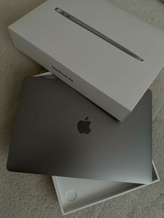 two apple laptops sitting next to each other on the floor in front of a box