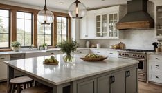 a large kitchen with white cabinets and marble counter tops, two pendant lights over the island