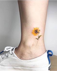 a sunflower tattoo on the ankle is shown in front of a woman's foot