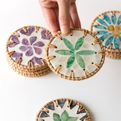 three handmade coasters made out of paper and wicker with flowers painted on them