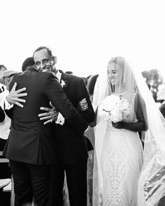 a bride and groom hug as they walk down the aisle