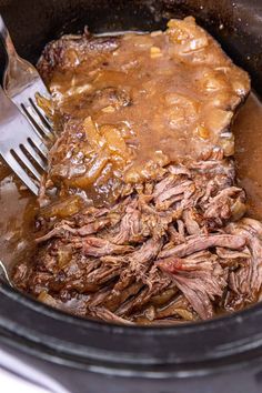 pot roast with gravy in the slow cooker being eaten by a fork