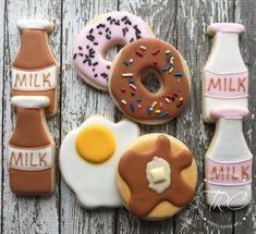 decorated cookies with milk, donuts and eggs on a wooden table next to each other