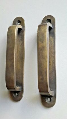 two metal door handles on a white surface