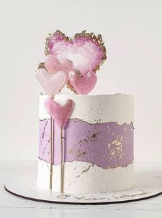 there is a cake decorated with pink and purple hearts on the top, as well as gold trimmings