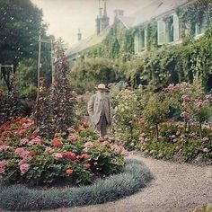 an old photo of a man standing in the middle of a garden with lots of flowers