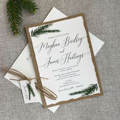 the wedding stationery is laid out on top of two envelopes and tied with twine