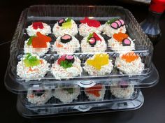 a plastic container filled with cupcakes covered in white frosting and gummy bears