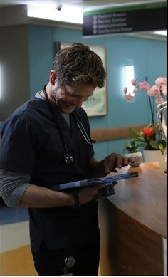 a man in scrubs is writing on a clipboard