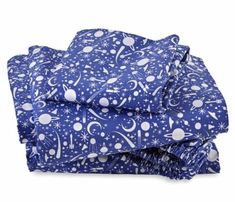 a blue sheet set with white stars and planets on it, sitting on top of each other