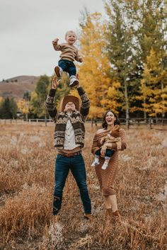 a man and woman are holding up a baby in the middle of an open field