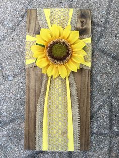 a sunflower is placed on top of a piece of wood that has been painted yellow