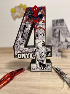 the number four is made out of comic book pages and sits on a table next to scissors