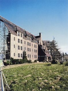 an old building with scaffolding on the roof and grass in front of it