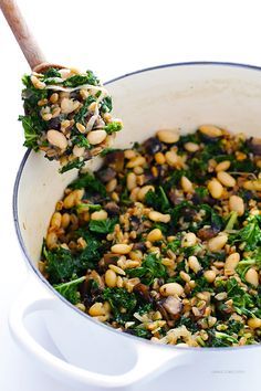 a white pot filled with greens and beans