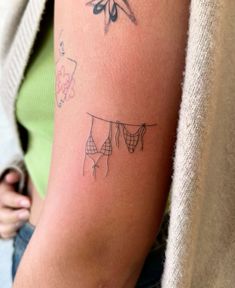 a woman's arm with tattoos on it and clothes hanging out to dry them