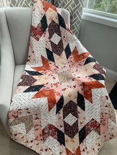 a quilted blanket sitting on top of a chair in front of a windowsill